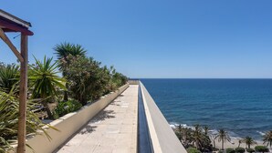 A seaside promenade with a concrete walkway, palm trees, and a view of the ocean. - Apartment with Shared Pool, Sea View, Wi-Fi and Air Conditioning (Marbella)