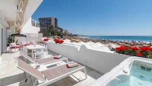 A rooftop terrace with a pool, lounge chairs, and a view of the beach and ocean. - Superb Spacious Seafront Apartment with Sea View, Wi-Fi, and Air Conditioning (Marbella)