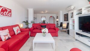 A living room with a red sofa, white coffee table, and a flat-screen TV. - Superb Spacious Seafront Apartment with Sea View, Wi-Fi, and Air Conditioning (Marbella)