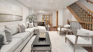 Ein modernes Wohnzimmer mit einem Ecksofa, einem Couchtisch und einer Treppe mit Holzbalkonen.