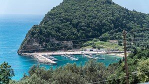 A coastal marina with boats, a rocky peninsula, and a clear blue sea.