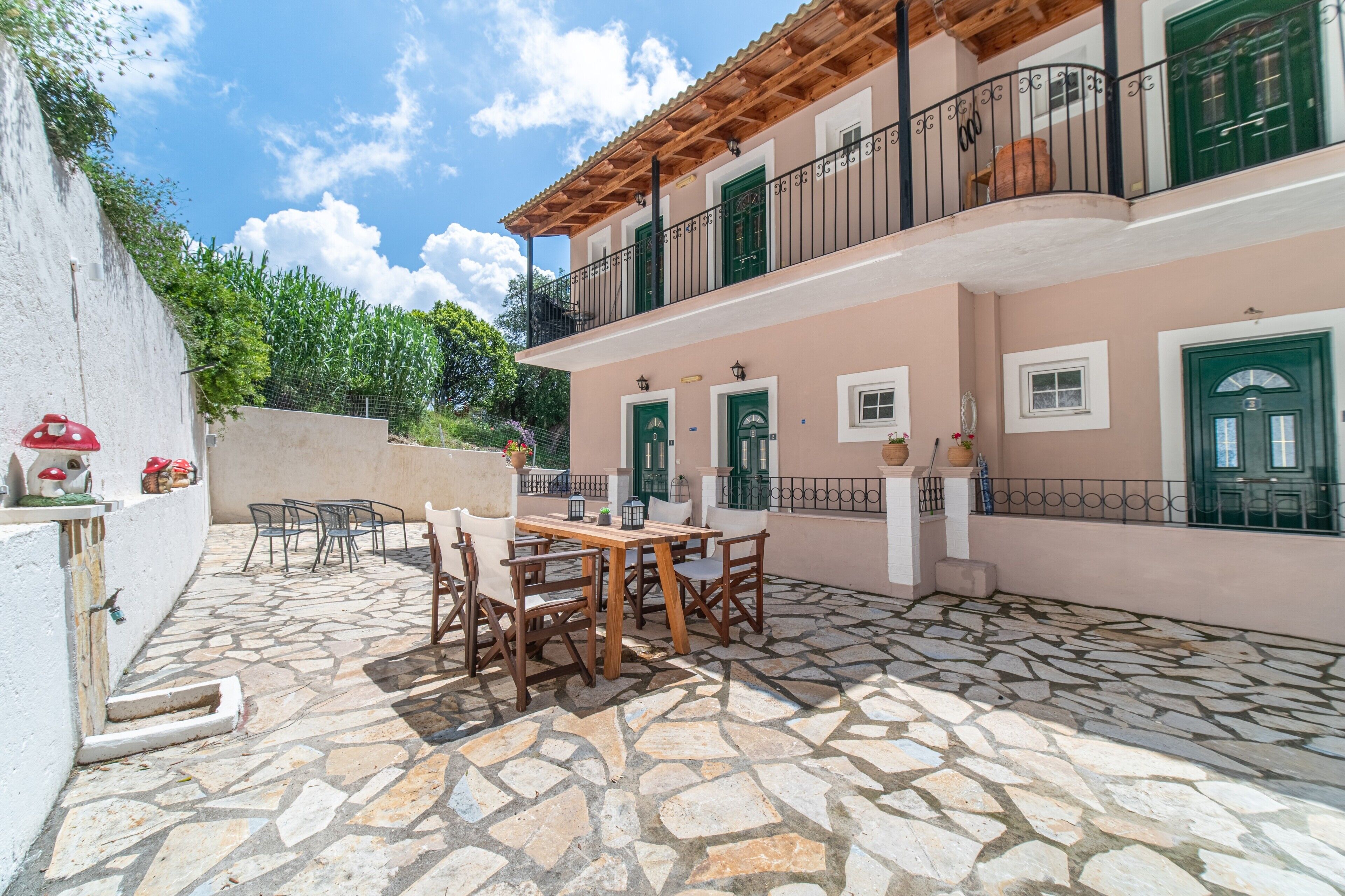 Un edificio con un patio de piedra, asientos exteriores y un balcón.