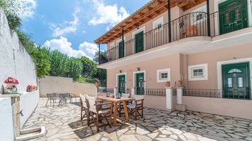 Un edificio con un patio de piedra, asientos exteriores y un balcón.