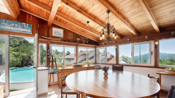 Un coin repas en bois, avec une grande table, des chaises et une vue sur une piscine.