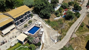 Vista aérea de una propiedad residencial con piscina, terraza cubierta y una calle.