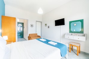 A hotel room with a bed, a TV, a small table, and a bench.