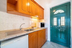 A kitchen with wooden cabinets, a microwave, a sink, and a dishwasher.