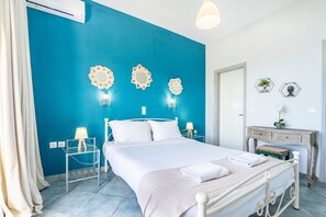 A bedroom with a bed, bedside tables, a dresser, and decorative wall mirrors.