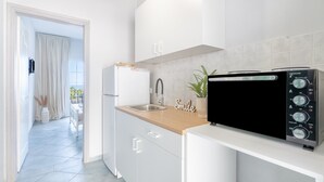 Une cuisine moderne avec des meubles blancs, un plan de travail en bois, un micro-ondes noir et un évier.