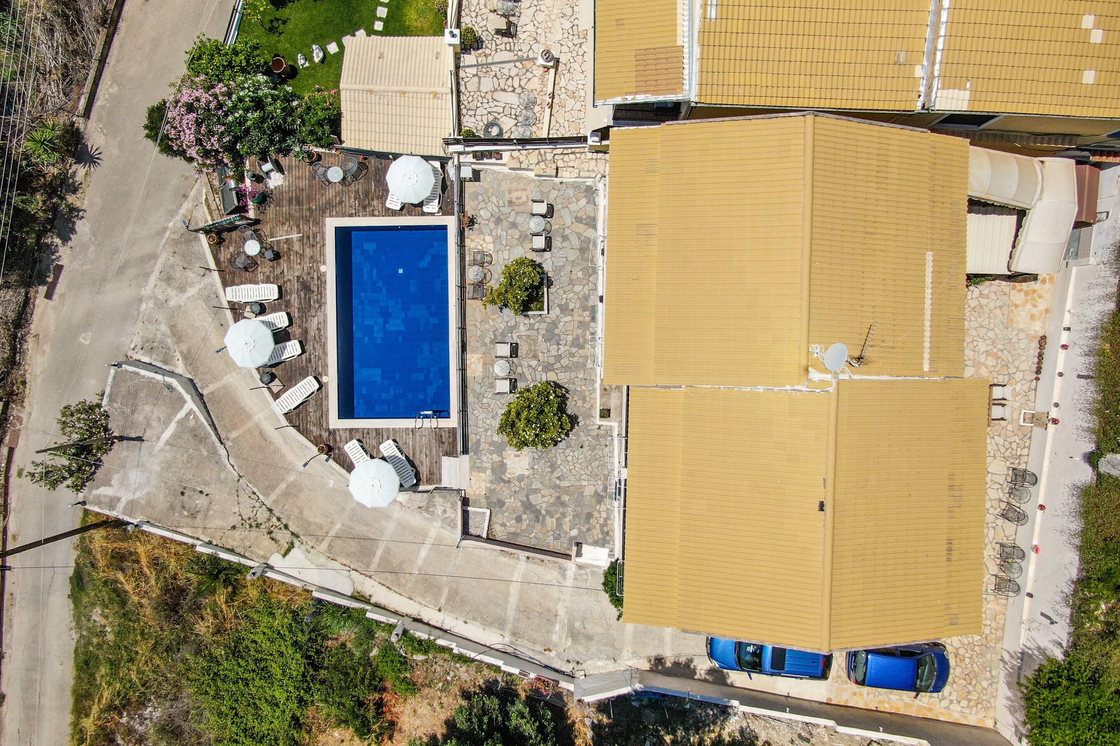 An aerial view of a property with a swimming pool, outdoor seating, and a covered patio area.