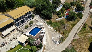 Vue aérienne d’une propriété résidentielle dotée d’une piscine, d’un patio couvert et d’une rue.