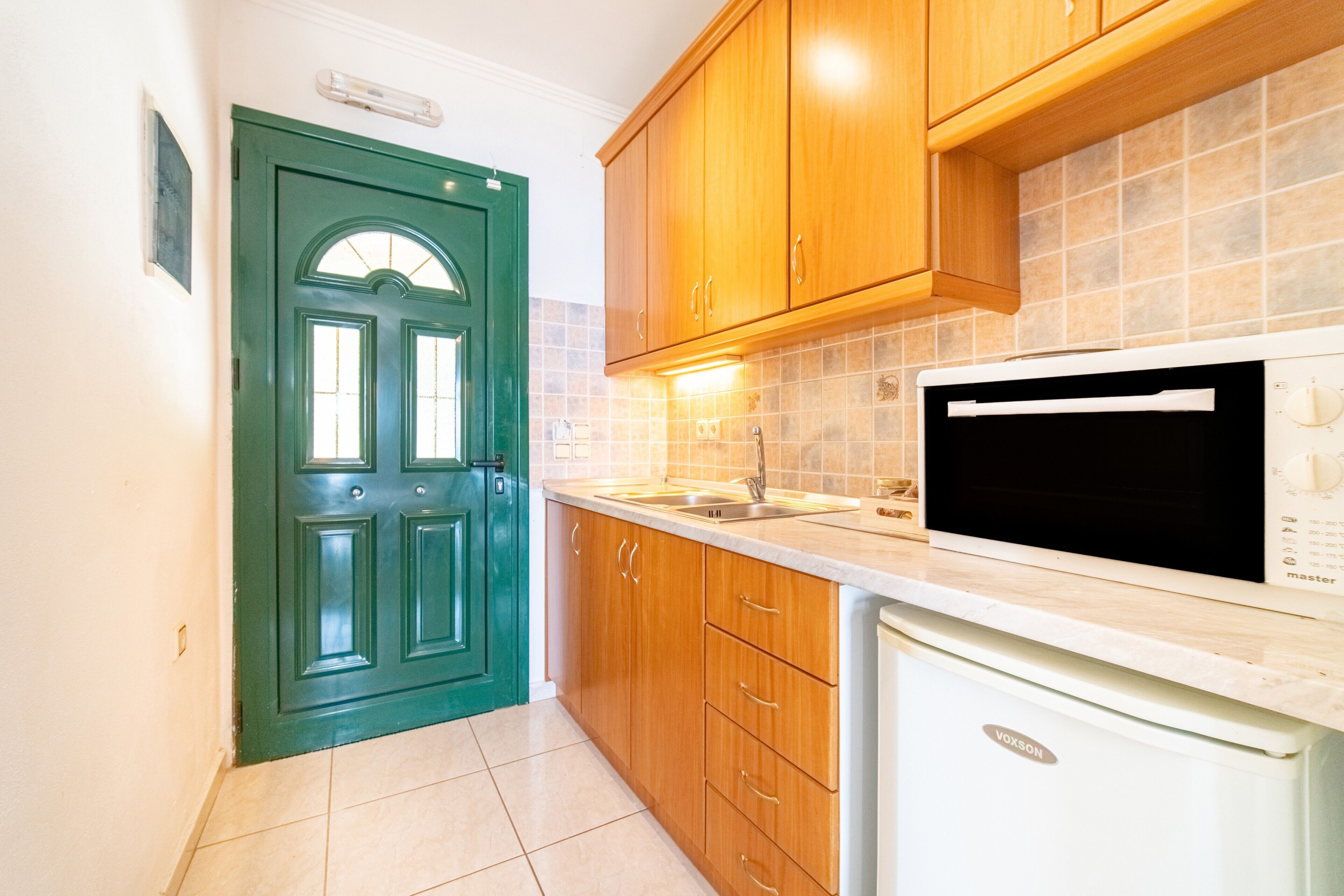 Una cucina con mobili in legno, un forno a microonde ed una lavastoviglie.