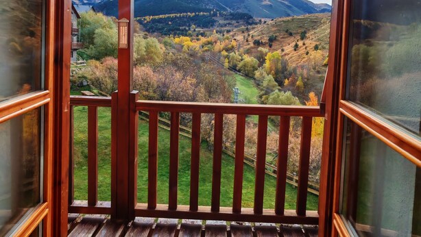 A wooden balcony with a view of a mountainous landscape.
