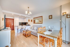 Una sala de estar moderna con una mesa de comedor, sillas, un sofá, una zona de cocina y un espejo grande.