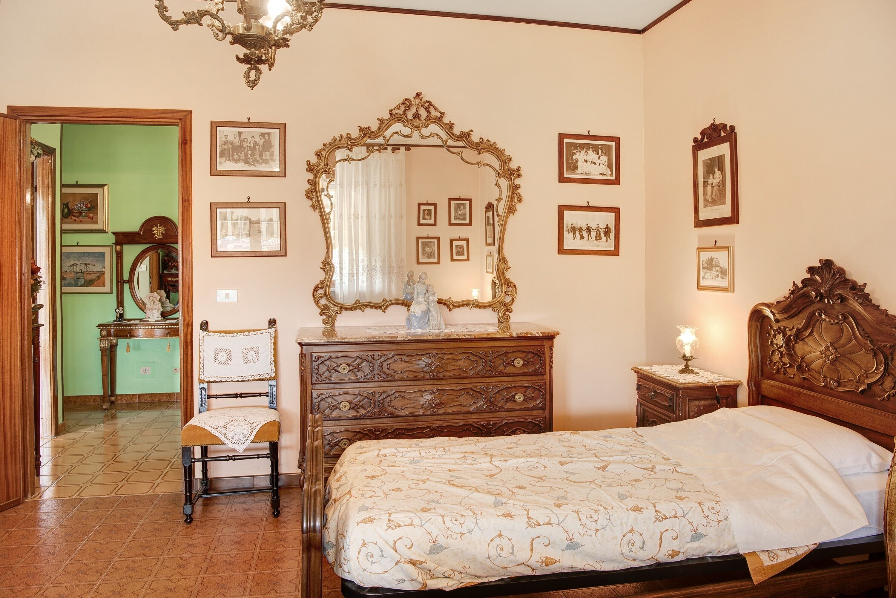 Ein Schlafzimmer mit Bett, Schminktisch, Stuhl und einem großen, verzierten Spiegel.