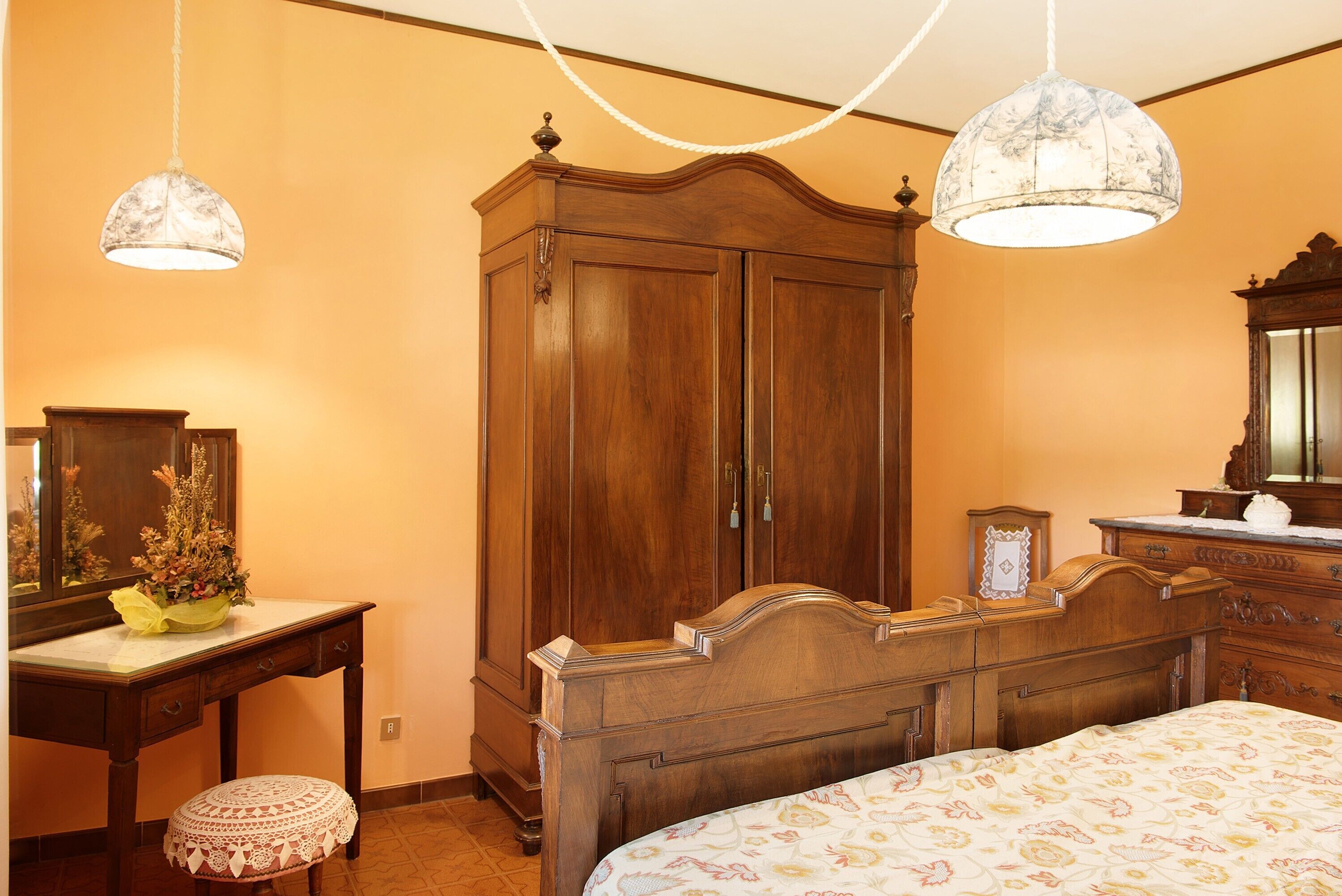 A bedroom with a wooden bed, a nightstand, a dresser, and a mirror.