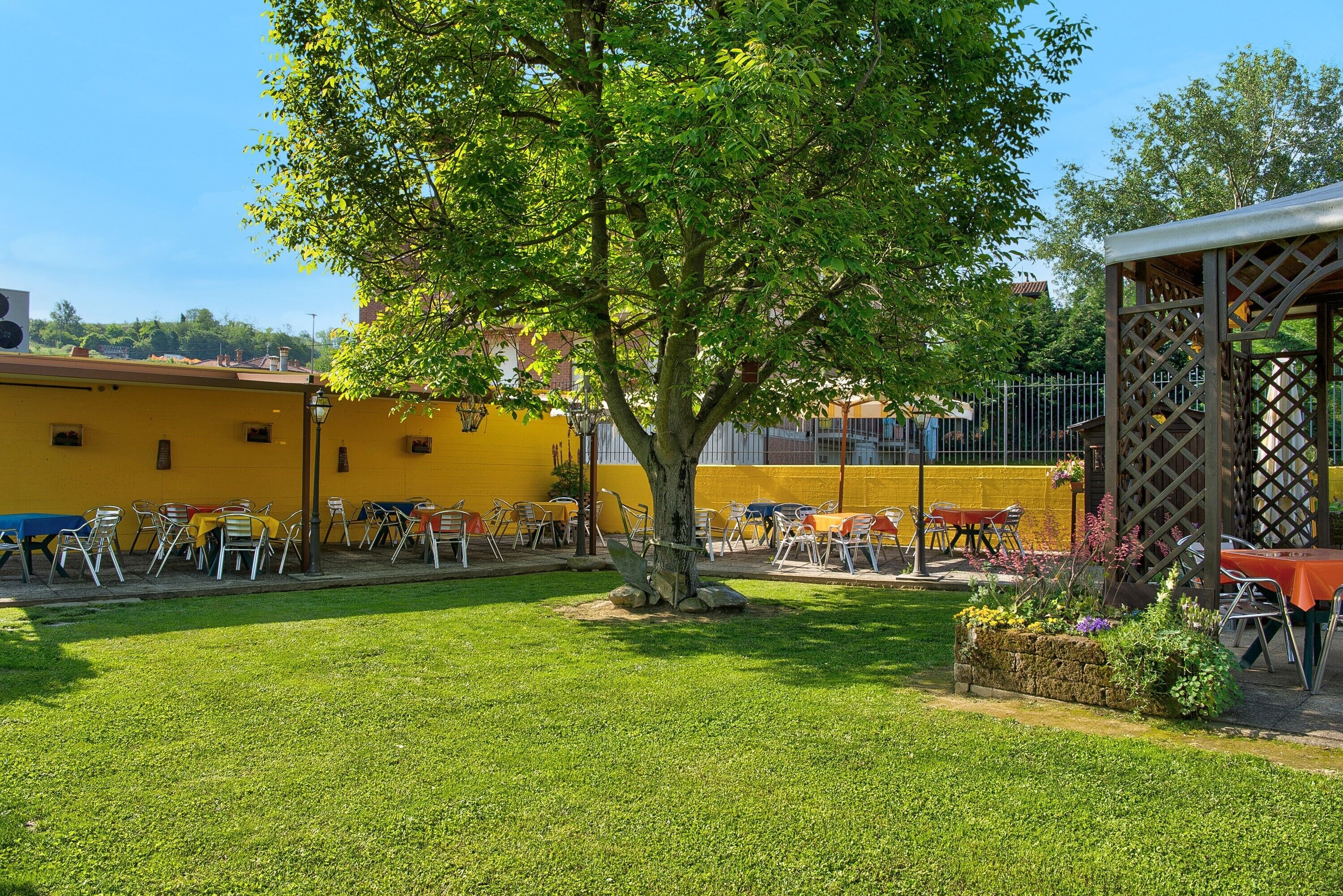A courtyard with a tree, outdoor seating, and a yellow building.