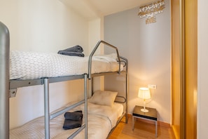 Habitación con literas, una mesita de noche pequeña y una lámpara fijada a la pared.