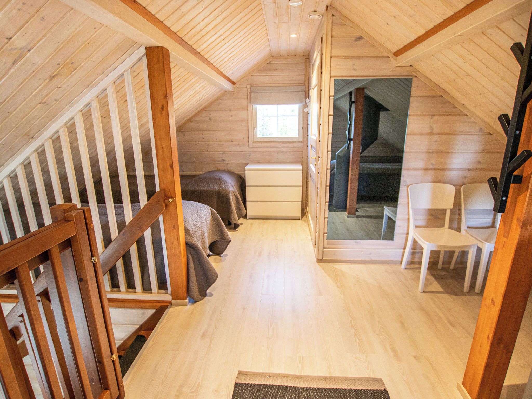 Un dormitorio acogedor en el ático con escaleras de madera, una cama, un aparador y vistas a otra escalera que sube a un nivel superior.