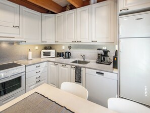 A modern kitchen with white cabinetry, a built-in oven, a microwave, a coffee maker, and a dishwasher. - Vacation home Arha by Interhome (Äkäslompolo)