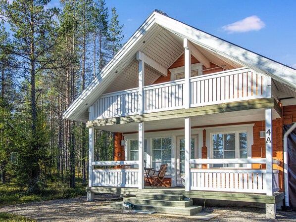 A two-story wooden house with a balcony, a porch with a bench, and a number '4A' sign.