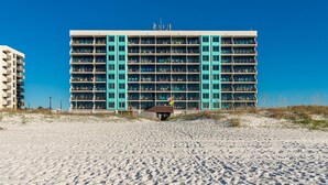 A multi-story hotel with a distinctive turquoise facade, located on a sandy beach. - Beach Front Condo with Bunks! (Gulf Shores)