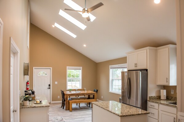A kitchen with a dining table, built-in appliances, and a ceiling fan.