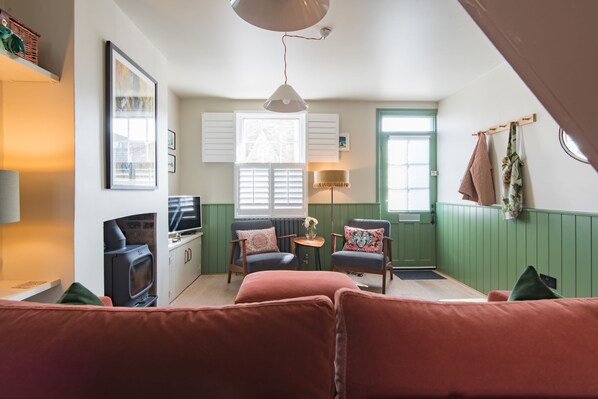 A cozy living room with a fireplace, comfortable seating, and a television. - Beautifully designed, stylish holiday home, seconds from the beach (Walmer, Deal)