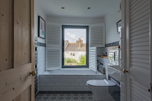 A bathroom with a window, white tiles, and a toilet. - Beautifully designed, stylish holiday home, seconds from the beach (Walmer, Deal)