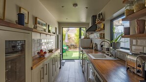 Une cuisine moderne avec des plans de travail en bois, un four encastré et une vue sur la terrasse extérieure.