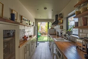 A modern kitchen with wooden countertops, a built-in oven, and a view to the outdoor patio. - Beautifully designed, stylish holiday home, seconds from the beach (Walmer, Deal)