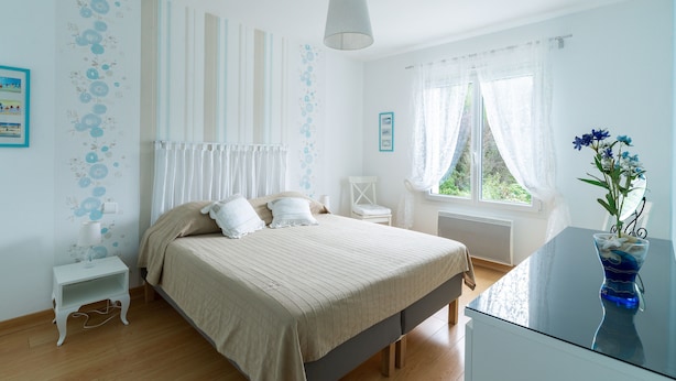 Une chambre à coucher avec un lit, une table de chevet et une fenêtre avec des rideaux.