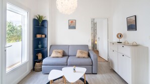 A modern living room with a grey sofa, white coffee table, and a blue shelving unit with decorative items.