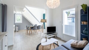 A modern living room with a staircase, a dining area, and a TV.