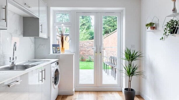 Una cocina moderna con lavadora, un lavamanos y una zona de comedor con sillas y una mesa.
