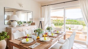 Un coin repas avec une table dressée pour quatre personnes, un miroir et une vue sur l’extérieur.
