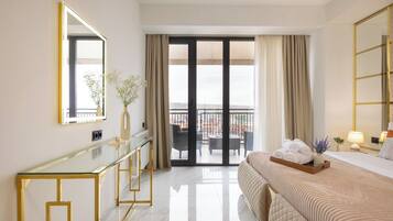 A hotel room with a bed, a bedside table, a mirror, a glass partition, and a view of the outside.