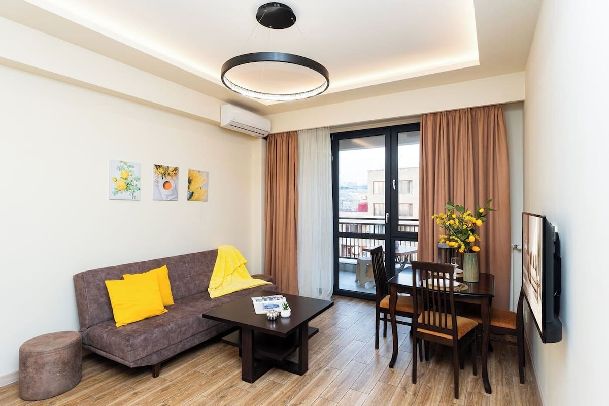 A modern living room with a sofa, coffee table, and dining area.