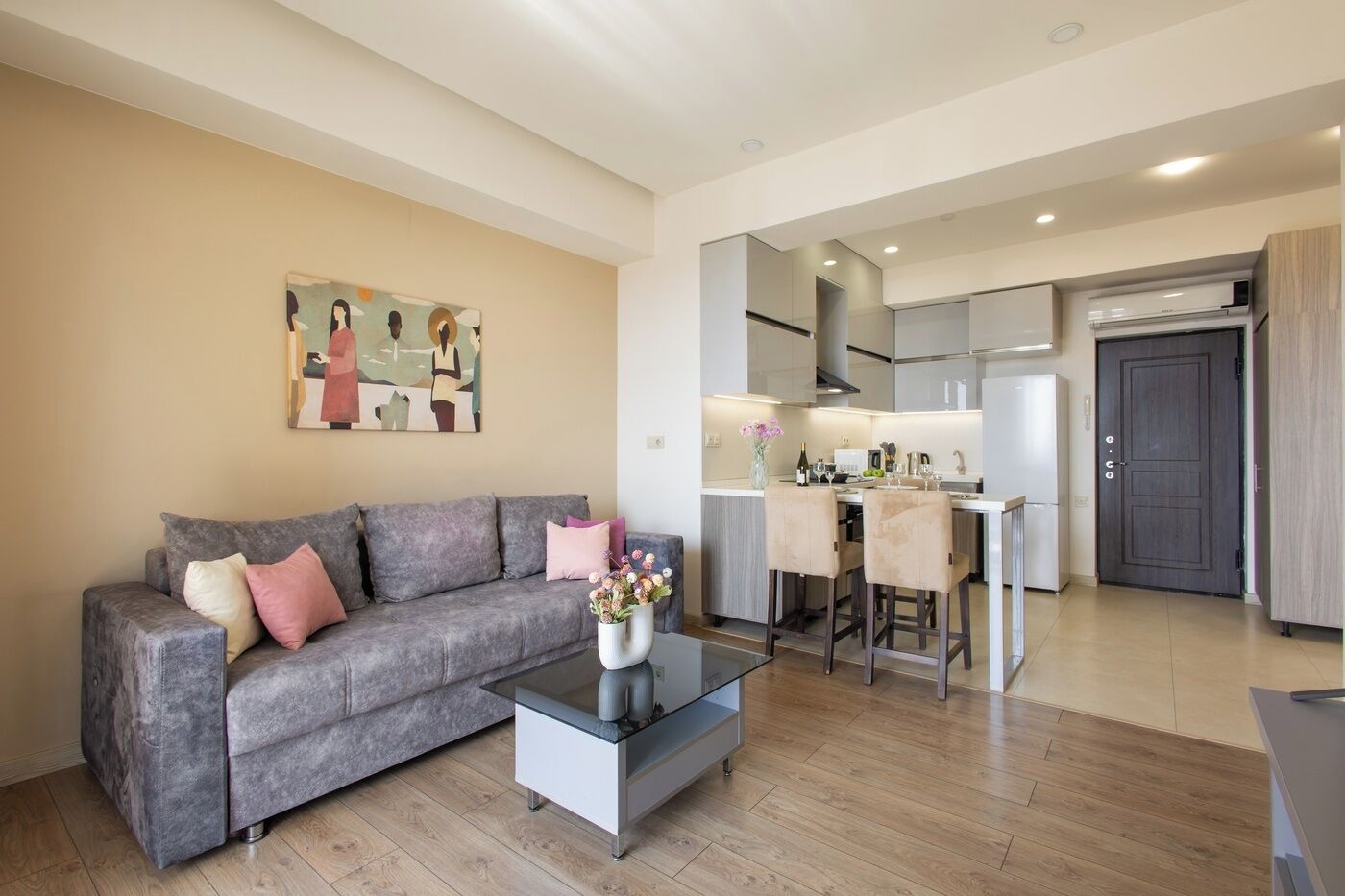 A living room with a grey sofa, a glass coffee table, and a painting on the wall.