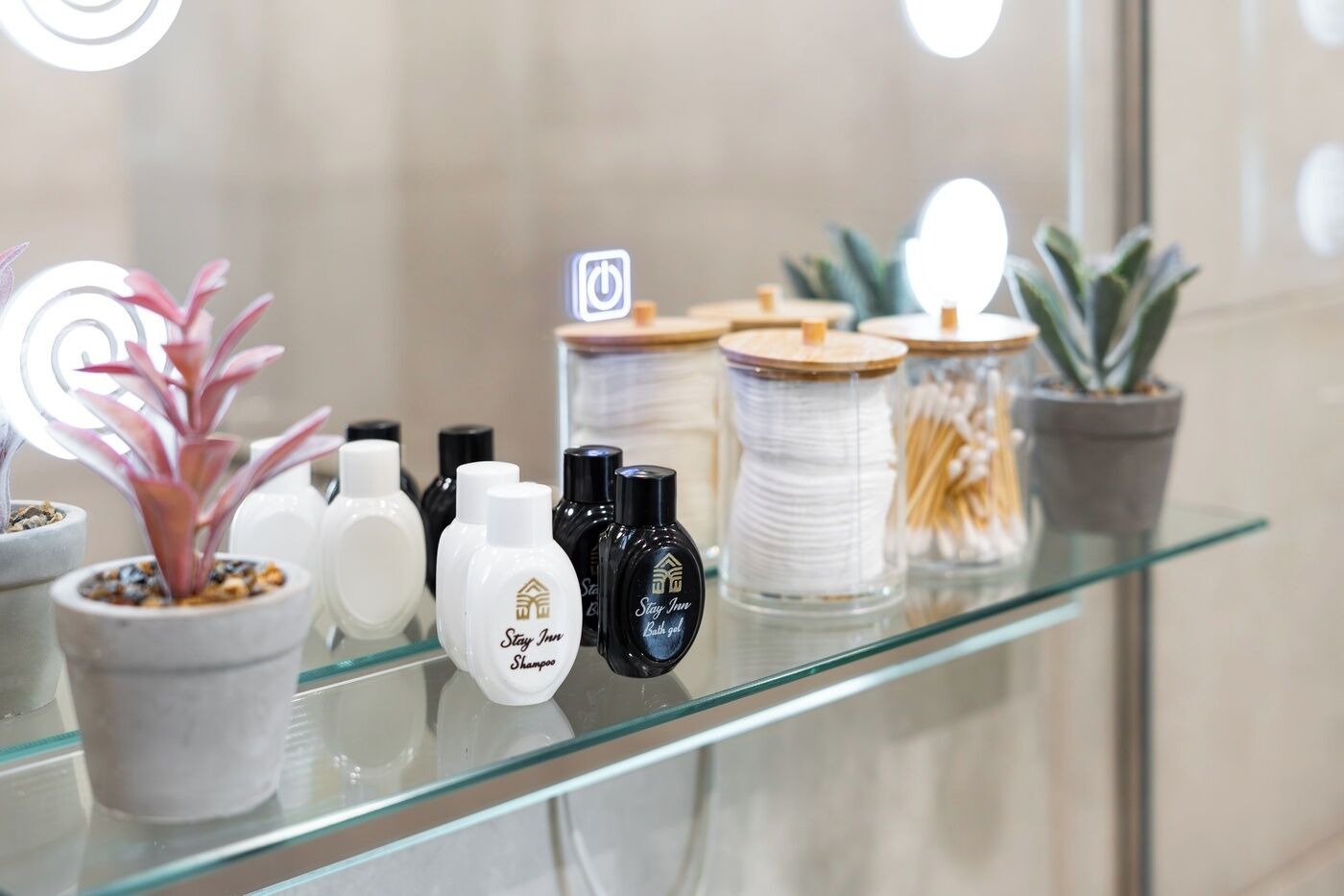 Une étagère en verre sur laquelle sont disposés divers produits de toilette, notamment des bouteilles de shampoing et de gel douche, ainsi qu'une bobine de fil blanc.