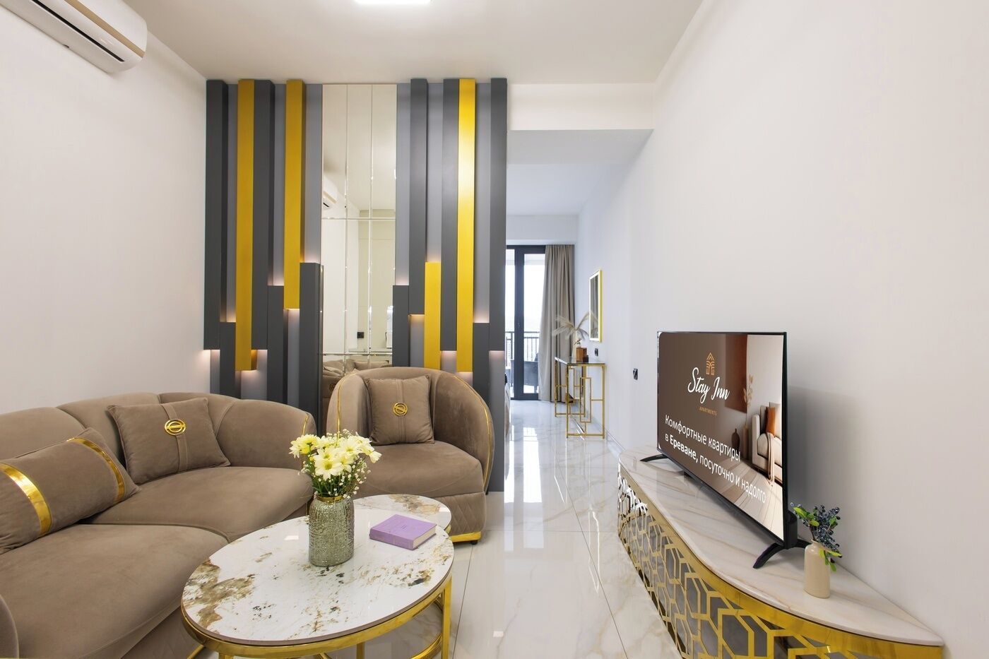 A modern living room with a sofa set, a coffee table, a TV, and a decorative wall panel.