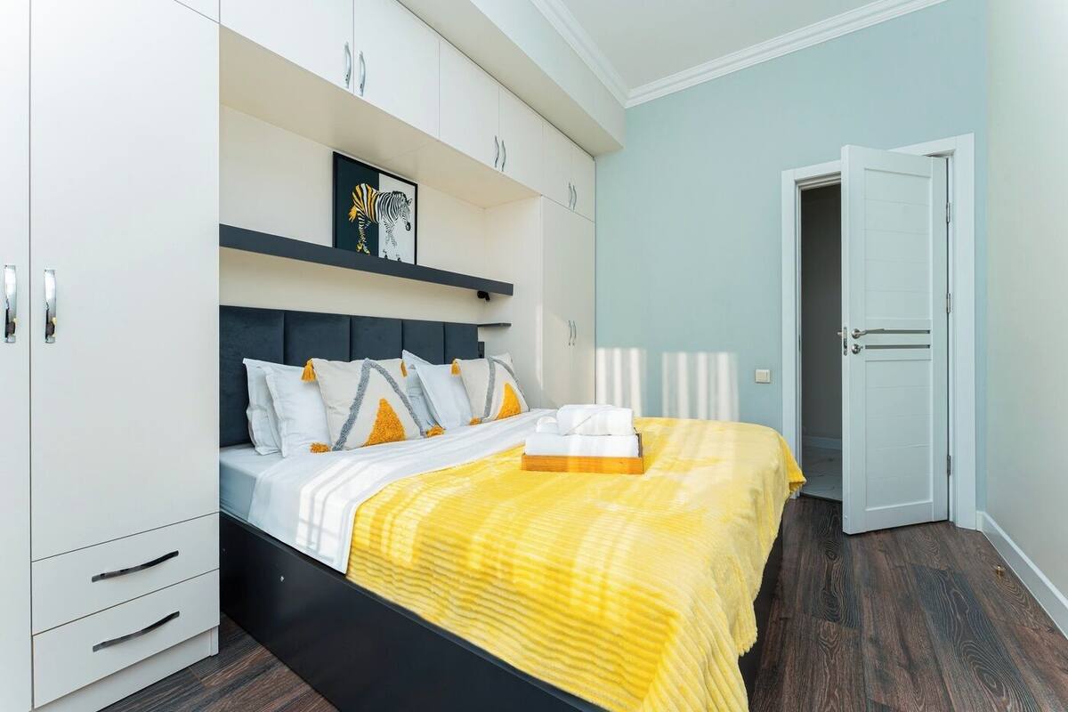 A bedroom with a bed, white wardrobe, and a door.