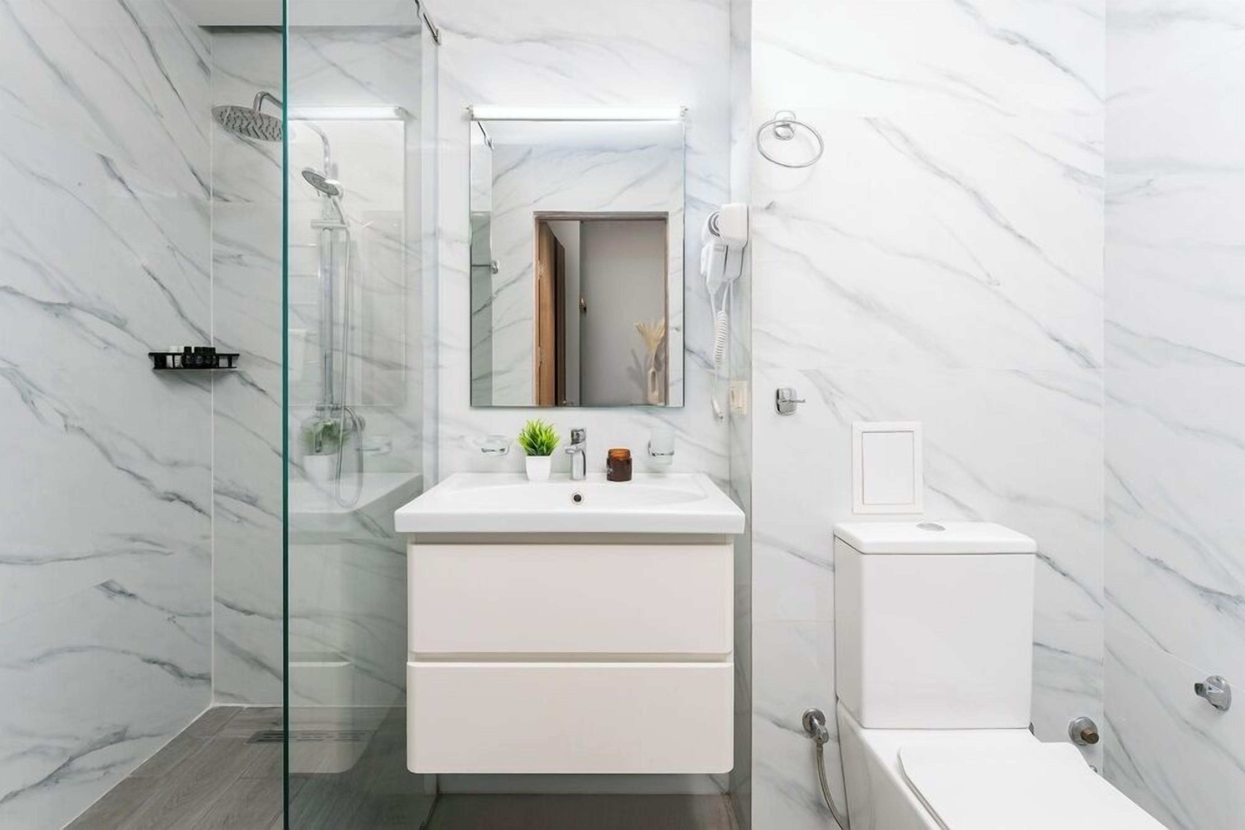 A modern bathroom with a glass shower enclosure, a white vanity with a mirror, and a toilet.