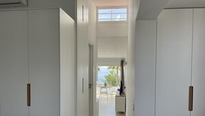 A corridor with white doors, a view of the sea, and a table with chairs outside. - Relaxing Ocean Views, Closed to the Beach (San Bartolomé de Tirajana)