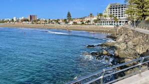 A coastal hotel with a rocky shoreline, clear blue waters, and a beach in the background. - Relaxing Ocean Views, Closed to the Beach (San Bartolomé de Tirajana)
