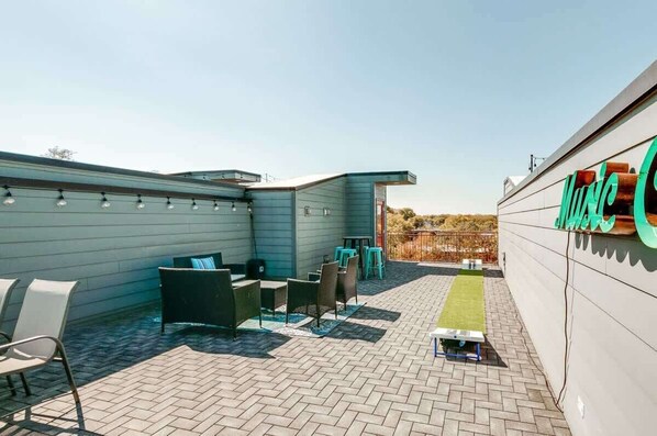 Un espace patio avec des sièges extérieurs, une petite table et un panneau sur le mur.