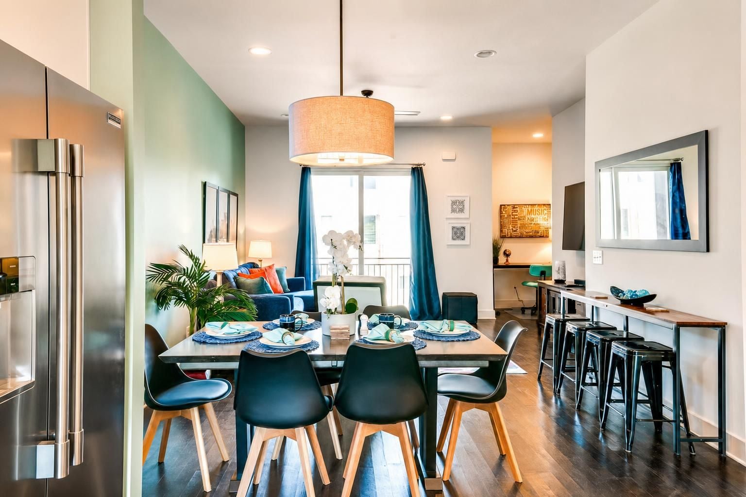 A modern kitchen with a dining area, stainless steel appliances, and a large pendant light.