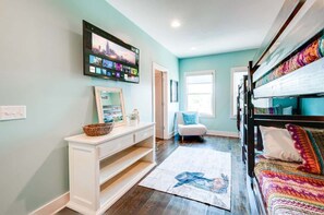 A room with a bed, a TV mounted on the wall, a white console table, and a window. - Nashville game room & bar house, sleeps 10, 3BR near Parthenon (Nashville)