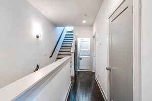 A narrow hallway with a staircase leading to a door, a washing machine in the corner, and a white wall. - Nashville group house with game room, full bar & themed bedrooms, sleeps 10 (Nashville)