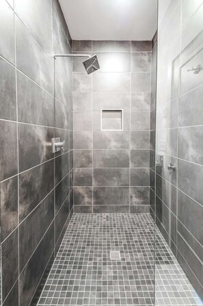 A modern shower with a glass door, tiled walls, and a grid-patterned floor. - Nashville game room & bar house, sleeps 10, 3BR near Parthenon (Nashville)